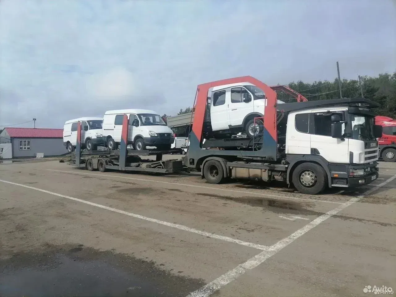 Автовоз Scania с коммерческими автомобилями на стоянке