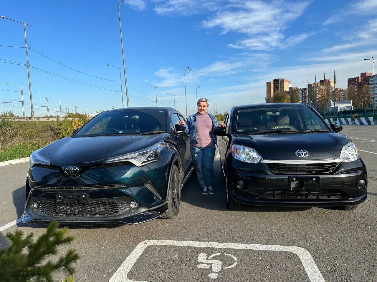 Клиентка рядом с доставленными автомобилями Toyota